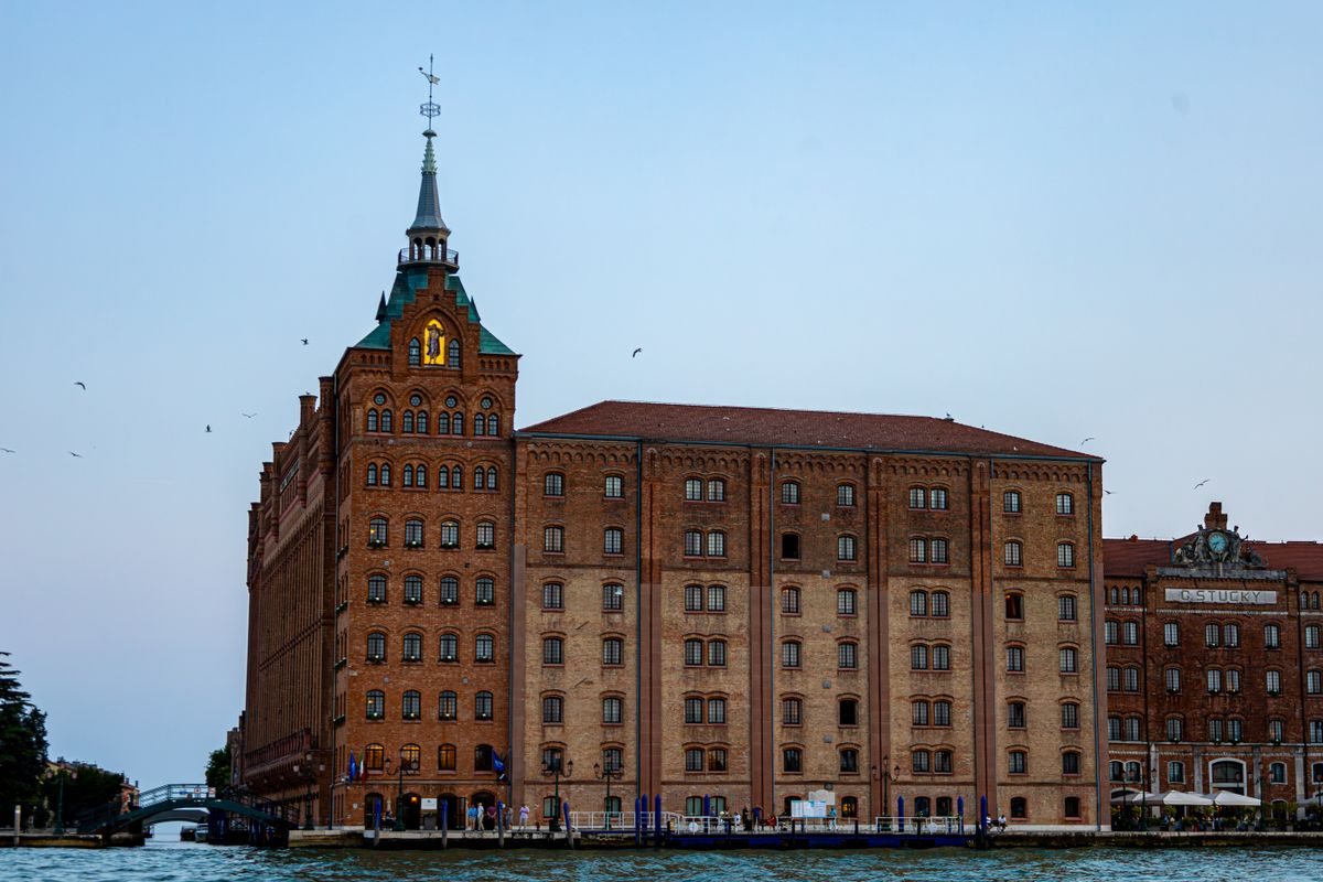 Vista do histórico edifício Molino Stucky em Veneza, Itália, com um céu sereno ao pôr do sol.