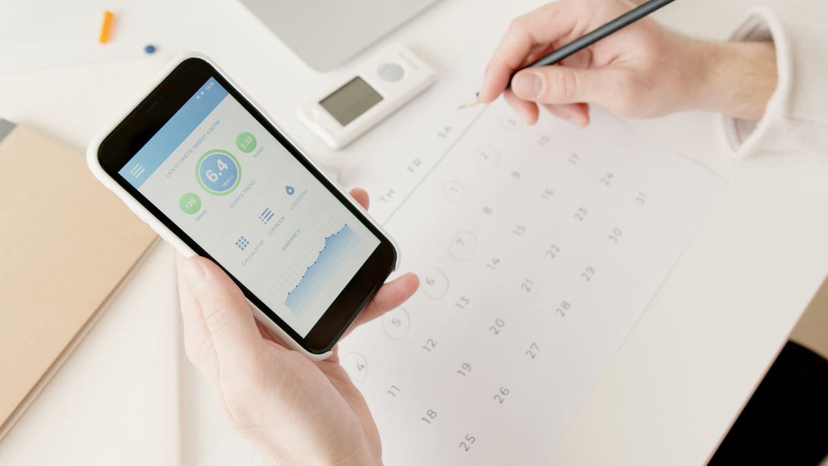 Mulher acompanhando o ciclo menstrual e a saúde reprodutiva no celular ao lado de um calendário — planejamento familiar educativo
